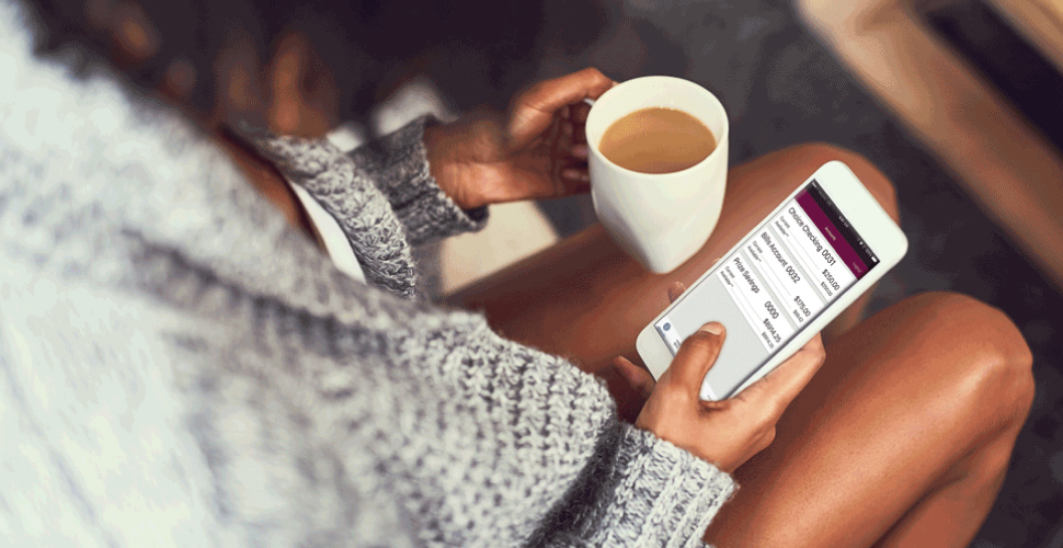 A girl looking at mobile phone with coffee in hand