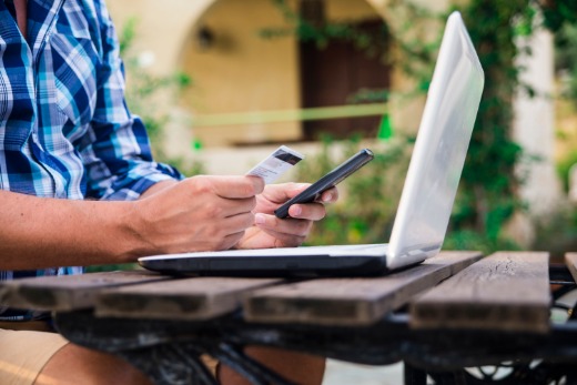 Man looking at credit card, and working on laptop computer