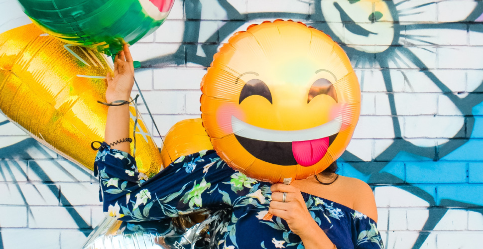A girl with emoji balloon in front of face