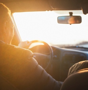 Man behind wheel of a car during sunset