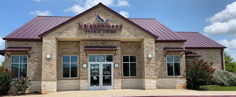 credit union branch exterior with bushes and blue sky