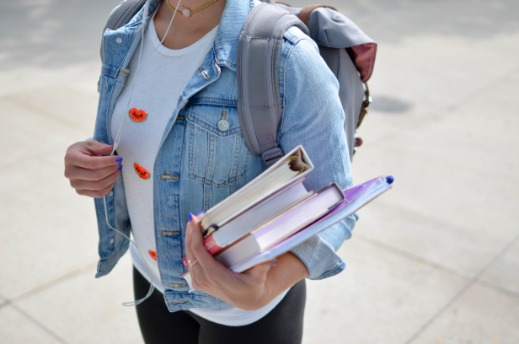 Person in backpack walking and holding books