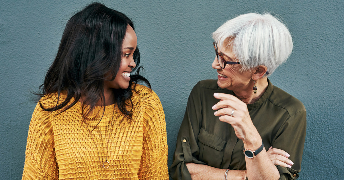 Shot of two cheerful businesswomen having a discussion while standing against a wall outdoors