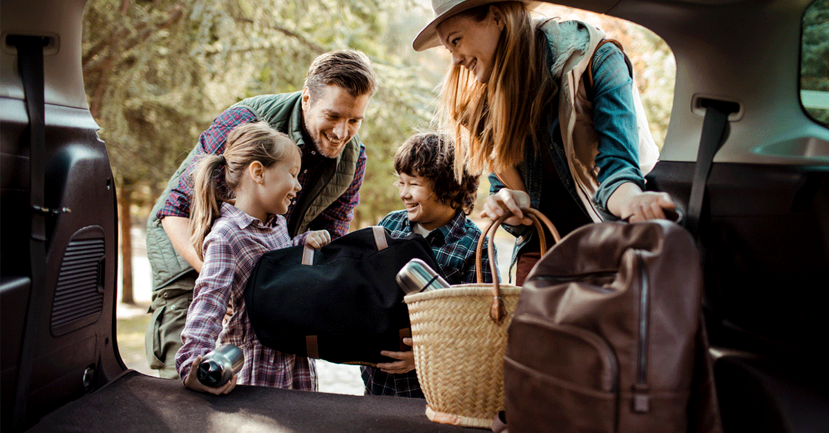 family smiling and loading up in the back of the car