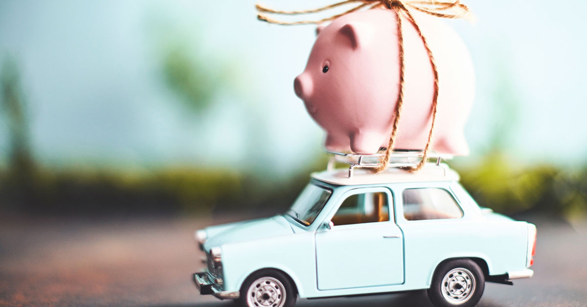 Little pink piggy bank tied to the top of an old toy car