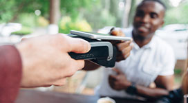 Close up of man making contactless payment in a cafe