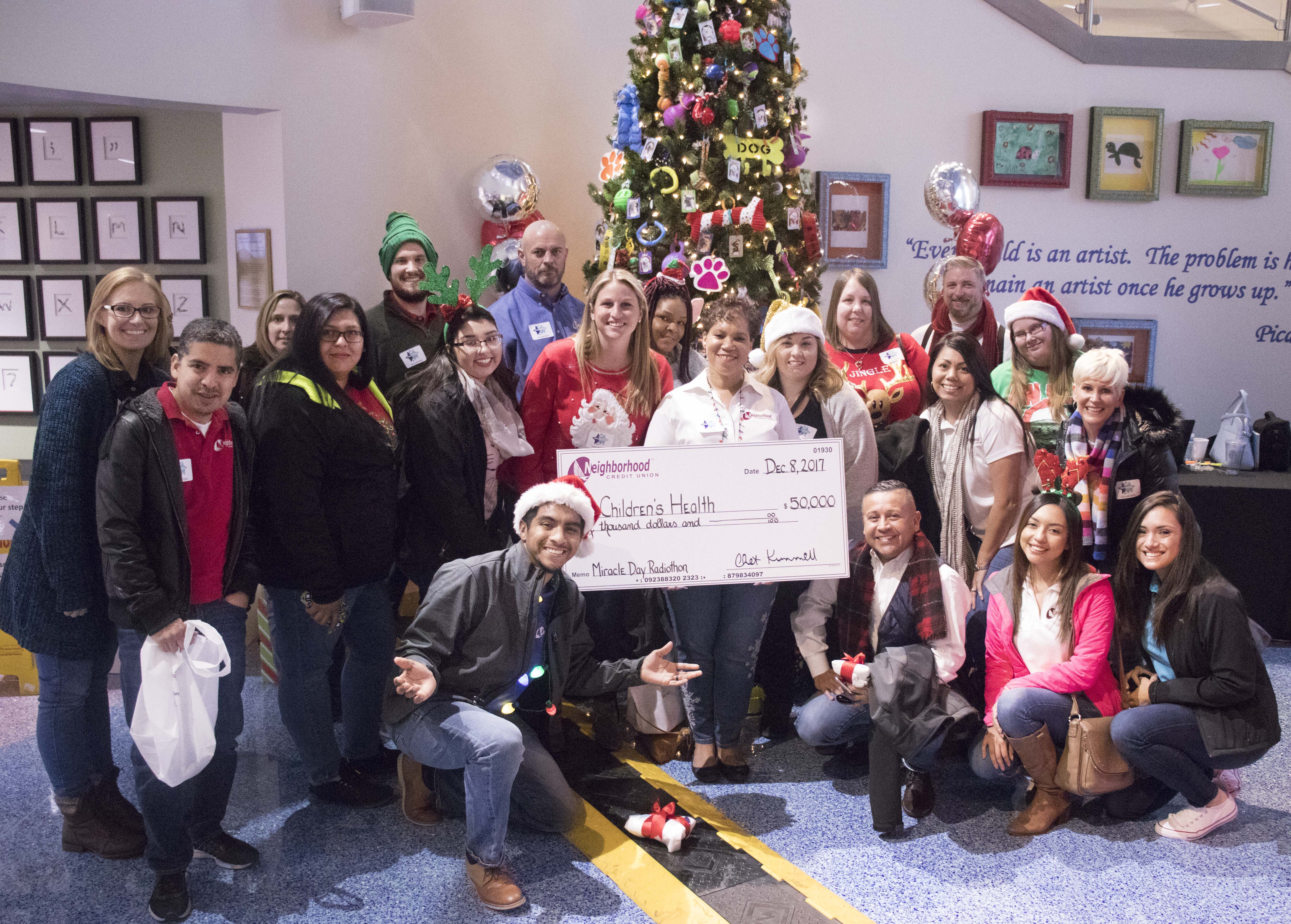 Group of employees around a christmas tree presenting a check