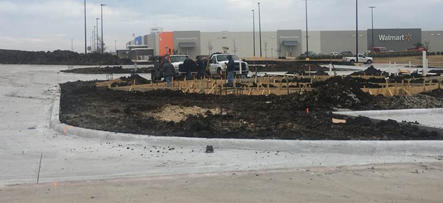 Still shot of a construction site, concrete drive is poured, freshly dug ground, and form of the building is starting to take place.