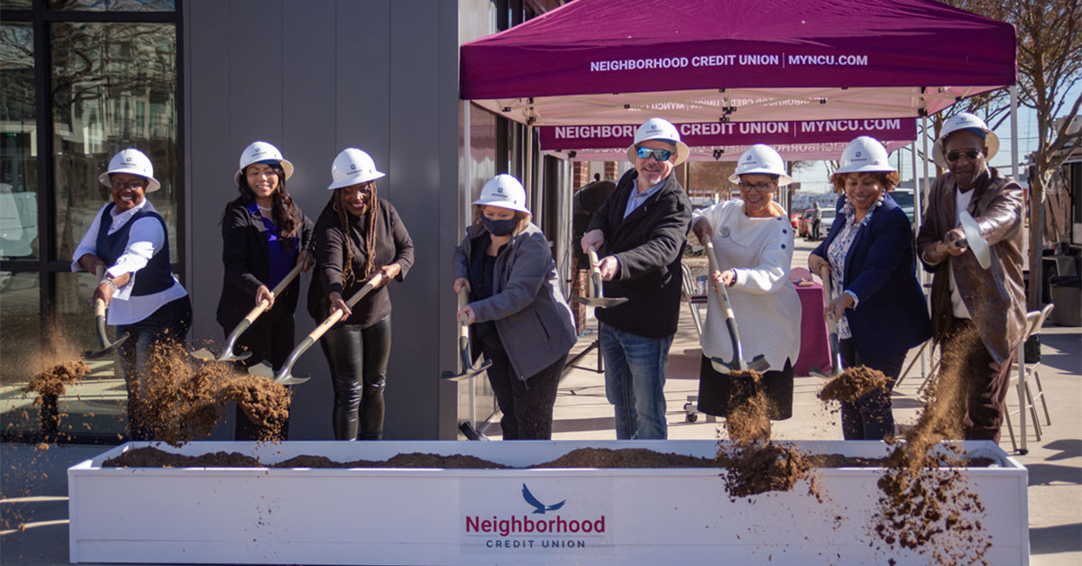 Still shot of Oak Cliff neighborhood representatives and Neighborhood CU representatives using shovels to "toss" the dirt towards the camera.