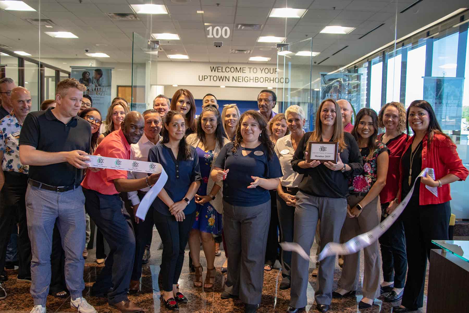 Group of Neighborhood Credit Union Employees standing behind ribbon, smiling and laughing