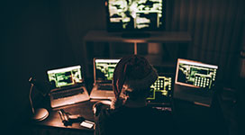 Computer hacker wearing santa hat while working on laptop late at night