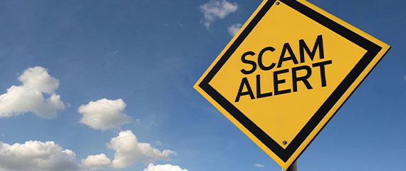 Still image of a yellow road sign with the words "Scam Alert"