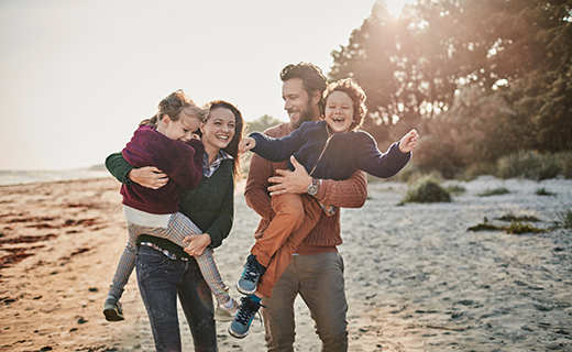 Husband and wife on the beach with two kids