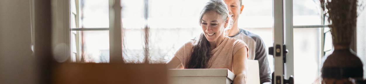 Couple moving boxes into house