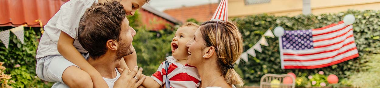 family in the back yard celebrating america with american flag and hats