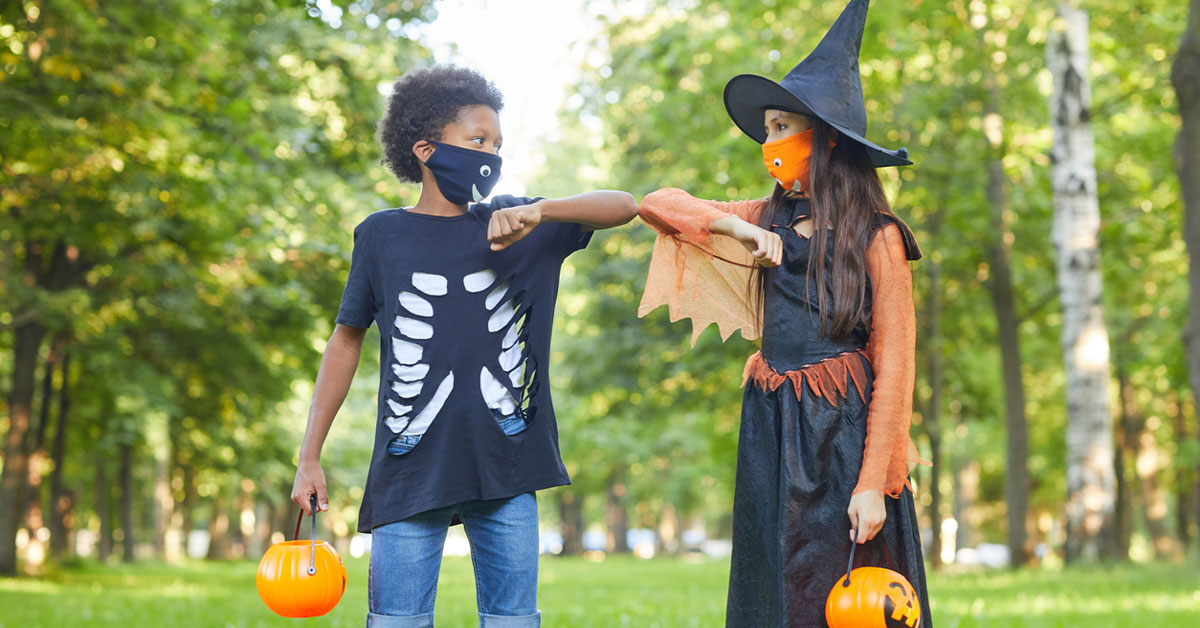 Two friends in Halloween costumes playing with each other in the park