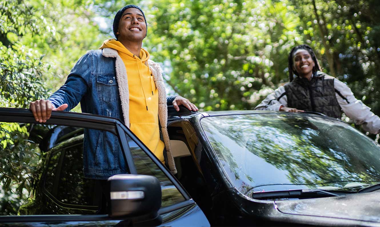 Friends contemplating and looking away from the car in a trail