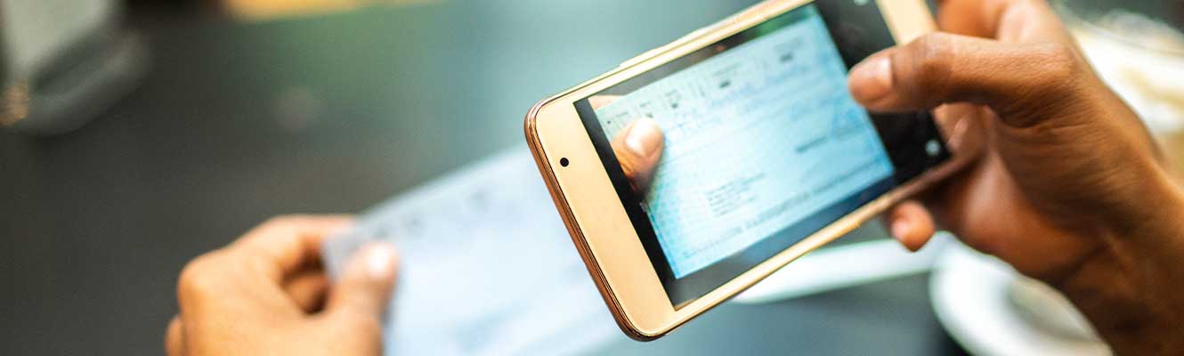 close up image of a man scanning a check to deposit it into his account 