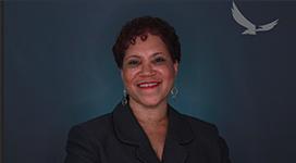 Carolyn Jordan in front of a backdrop looking at camera and smiling.