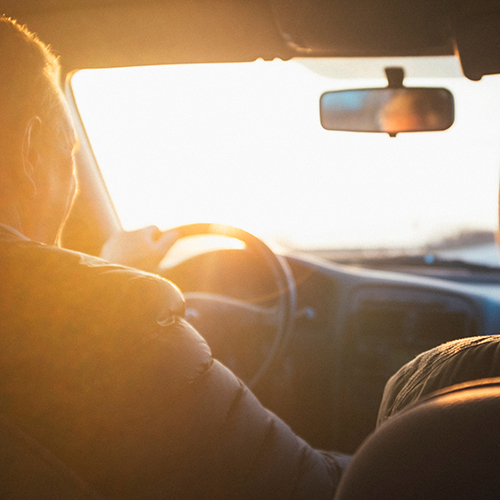 Man behind wheel of a car during sunset