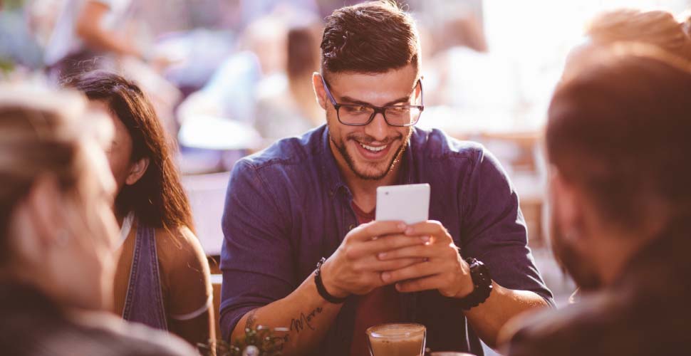 Man looking at cell phone with friends