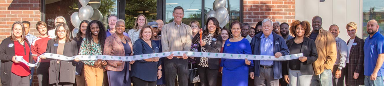 Still image of Neighborhood CU Employees and members, Local Mural Artist, and Oak Cliff representatives celebrating ribbon cutting.