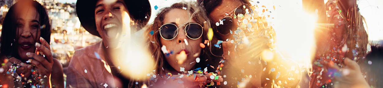 Group of friends blowing confetti 