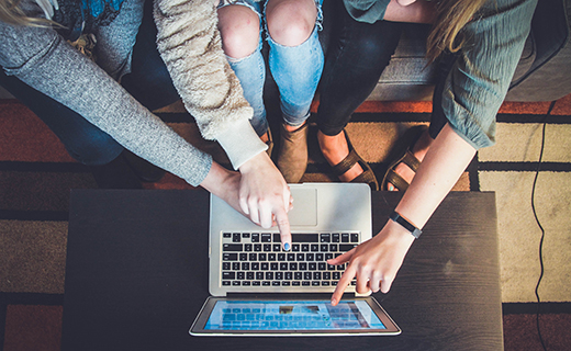 Three people pointing at a laptop