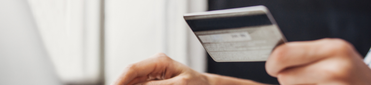 a person holding a debit card in front of computer