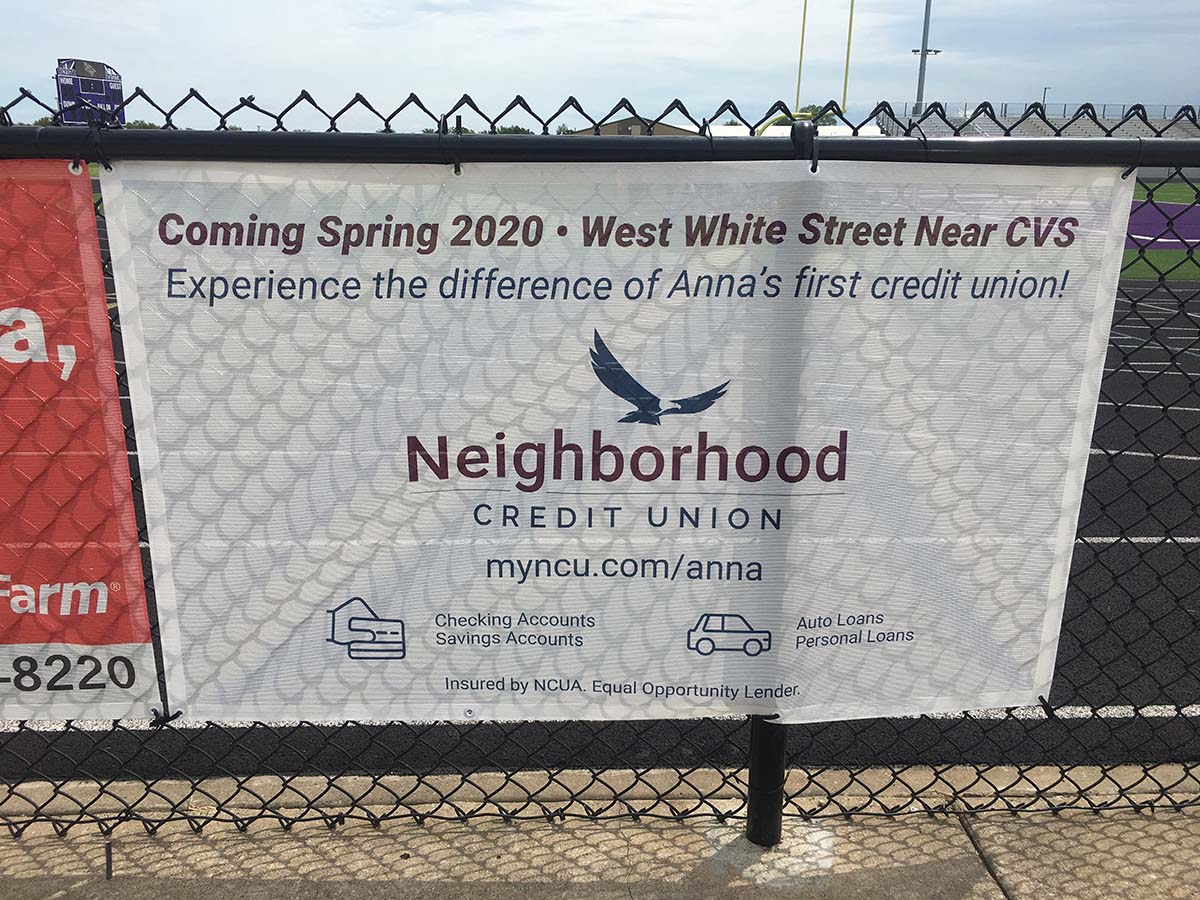 White banner hanging up on chain link fence