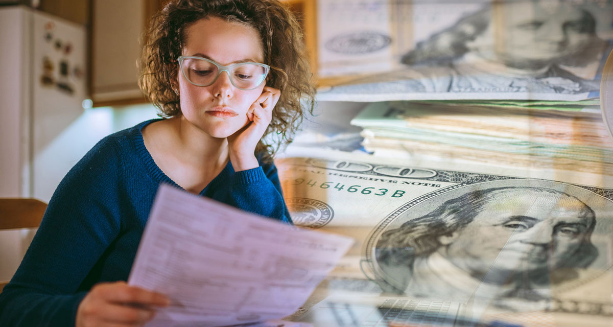 Young woman is looking at bills, feeling worried. Tax paying, bills, utilities concepts.