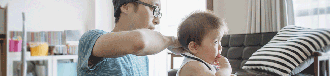 Father helping baby son eat.