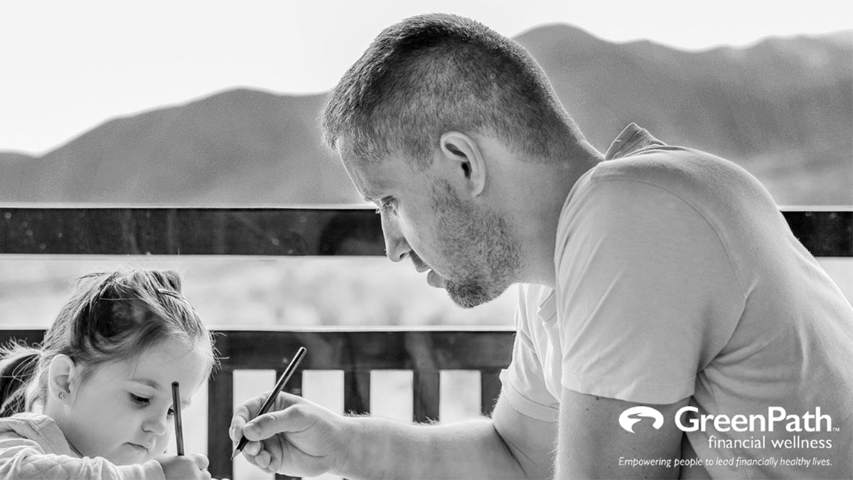 Man and child writing on a piece of paper together