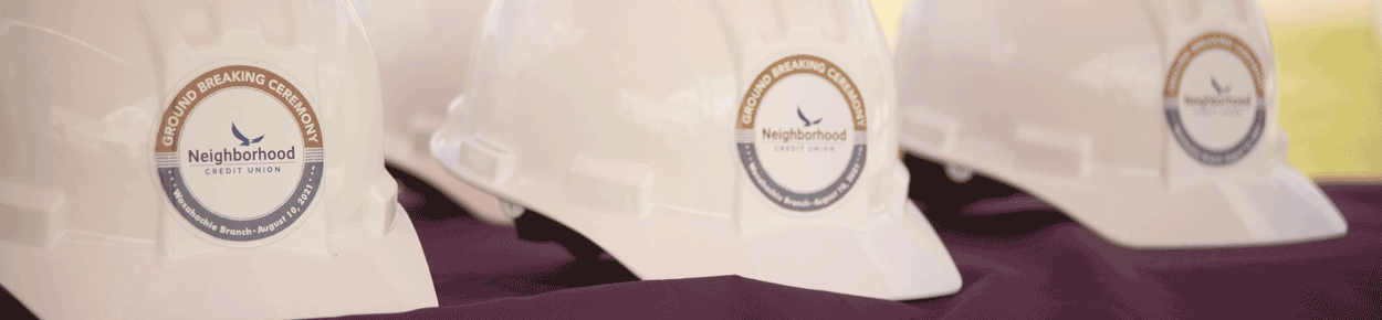 table of hard hats with sticker announcing groundbreaking