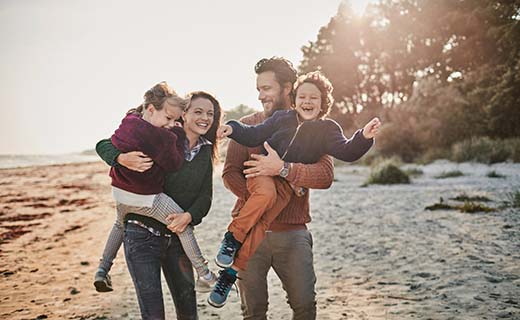 Husband and wife on the beach with two kids