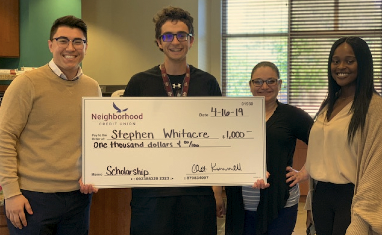 Group of people standing and smiling holding a large check