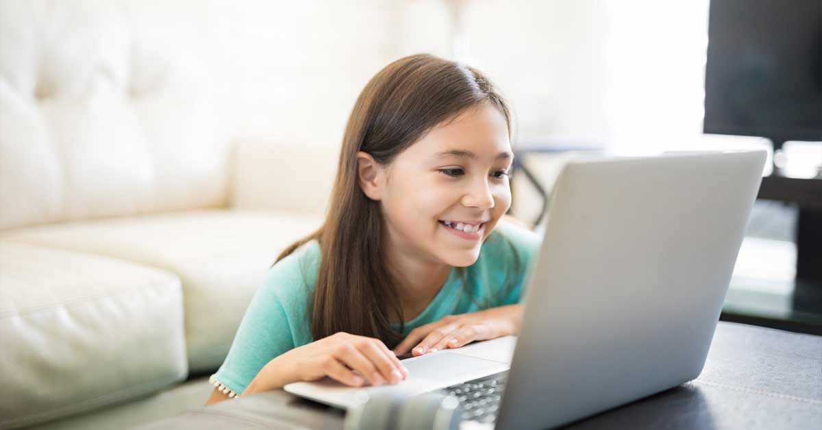 Young girl smiling and laughing at computer