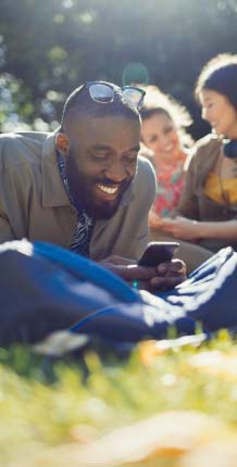 Man laying in the grass looking at his cell phone