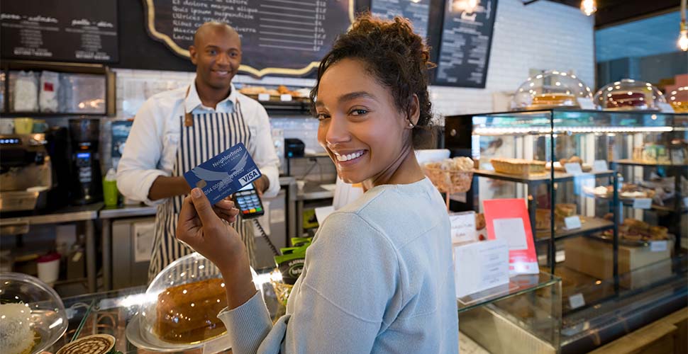 Woman holding debit card at bakery counter.