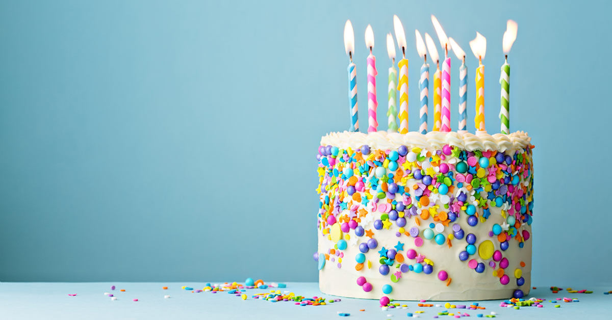 Still shot of a birthday cake with sprinkles and a blue background.