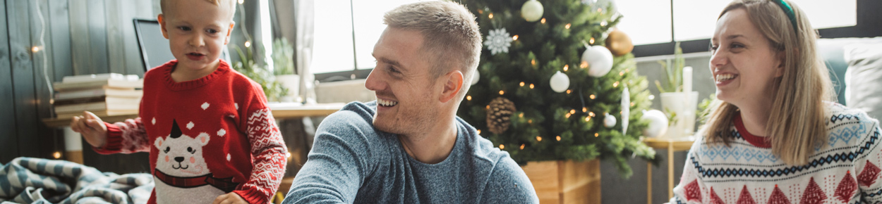 Father, mother, and son have fun in front of the Christmas tree