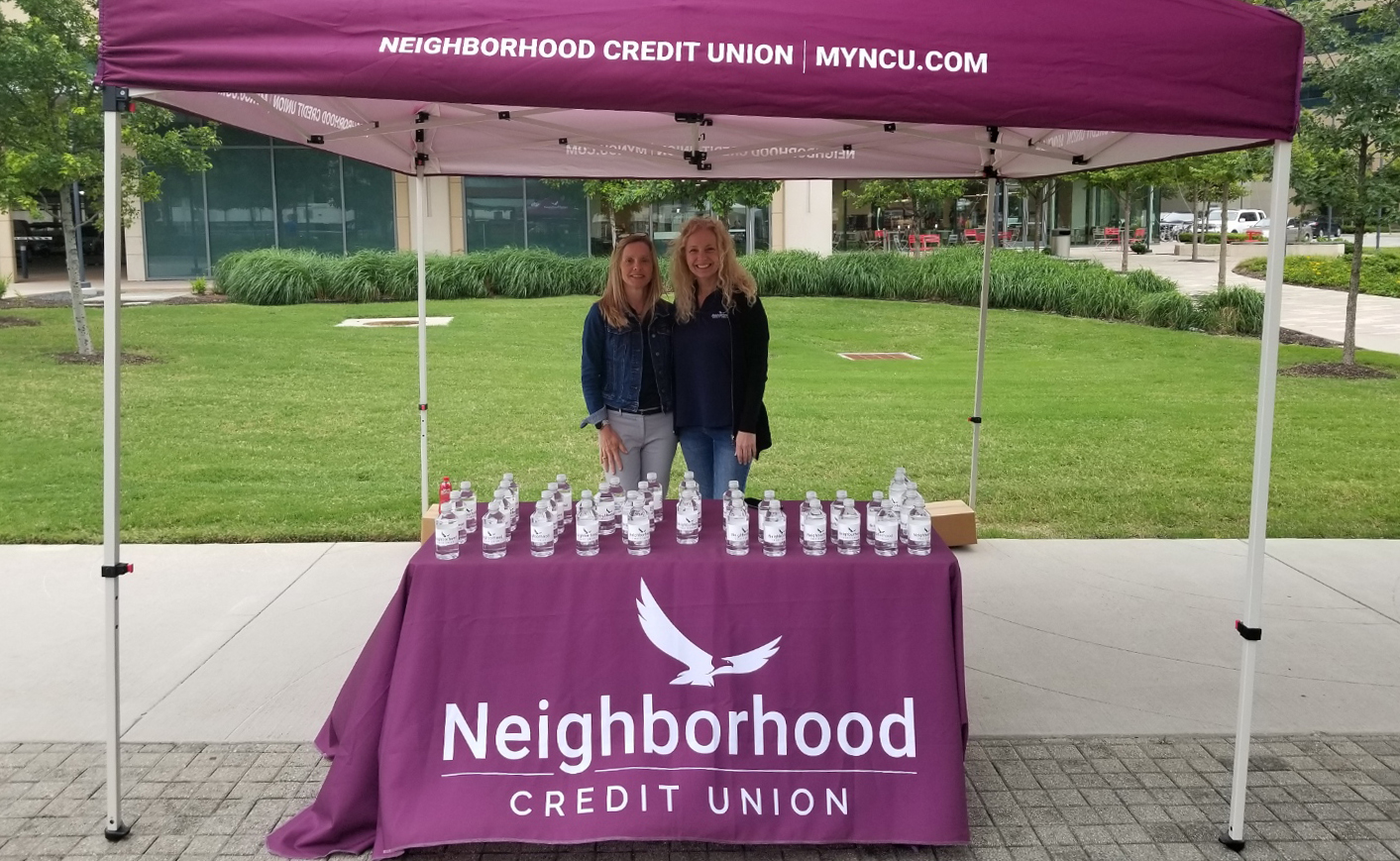 Two people standing under a tent outside