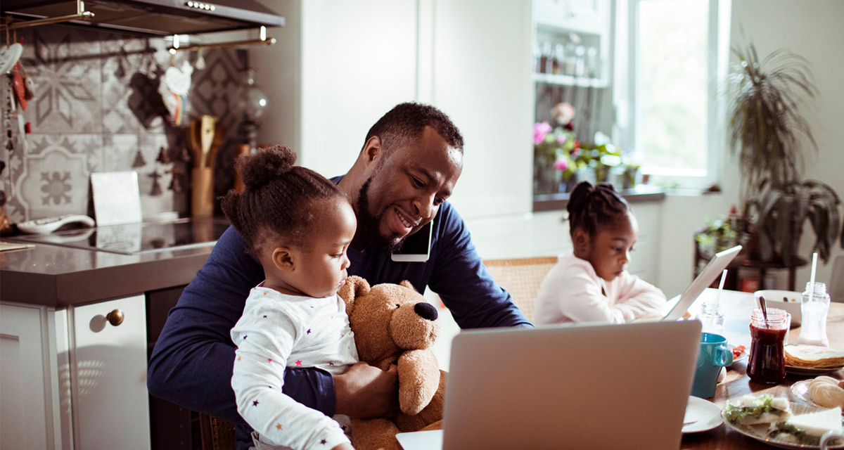 Close up of a young family using a laptop in the morning , while the father is talking on the phone