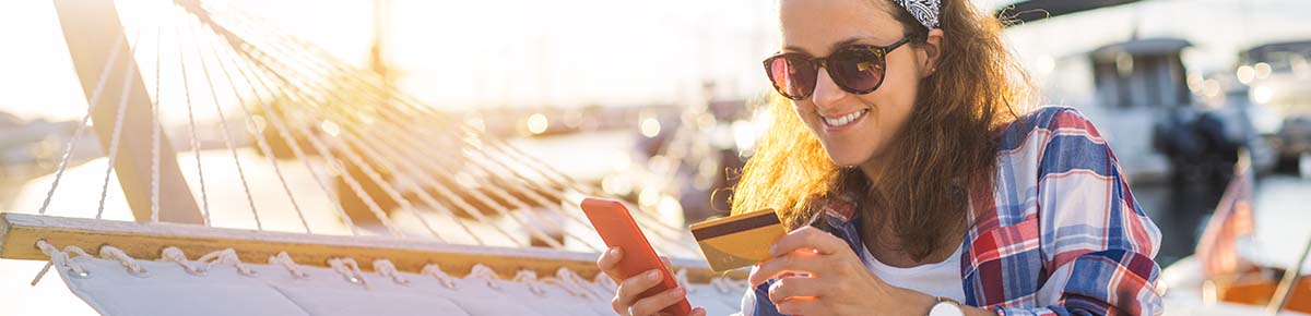 Woman on hammock smiling with credit card in hand