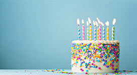 Still shot of a birthday cake with sprinkles and a blue background.