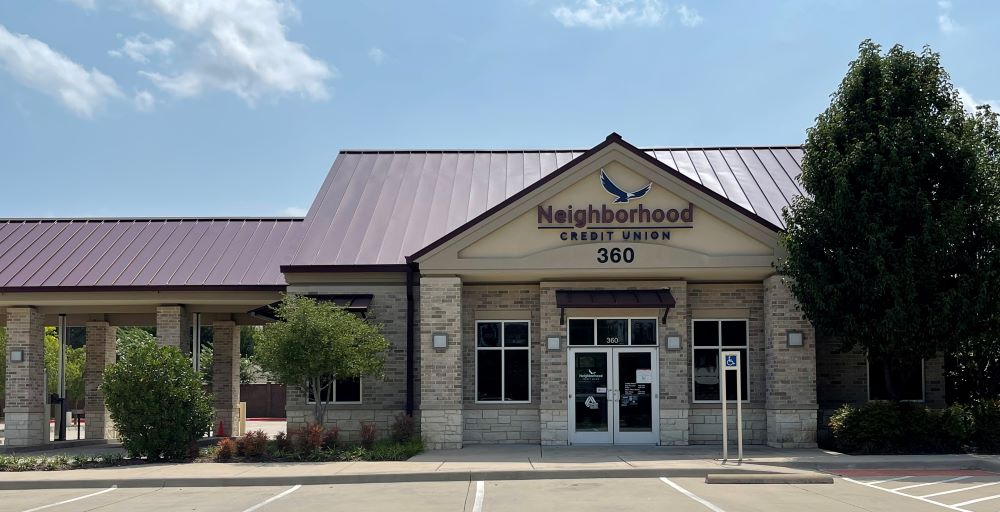 credit union exterior and drive thru lanes with trees and blue sky