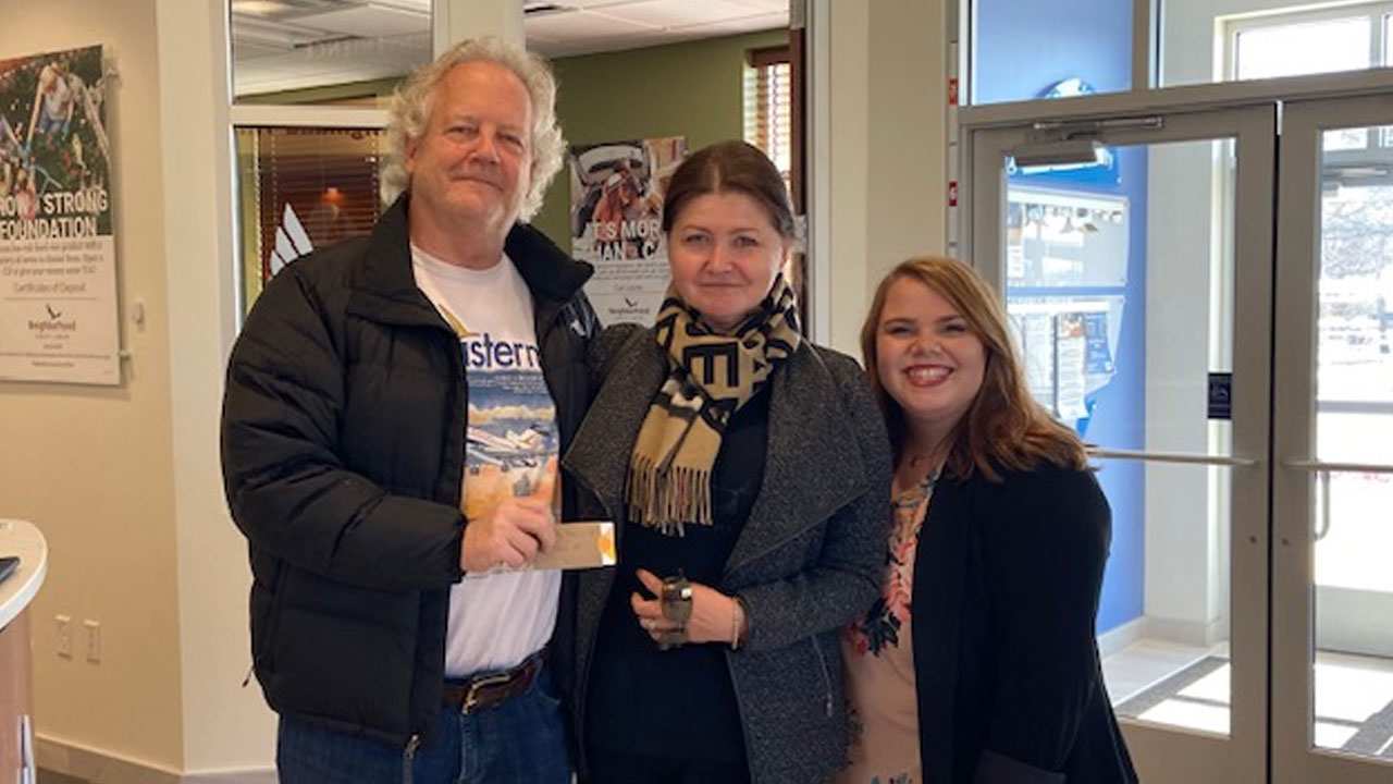 Neighborhood Credit Union members Mr. and Mrs. Pear and Financial Representative Kristen Groome smiling at camera.