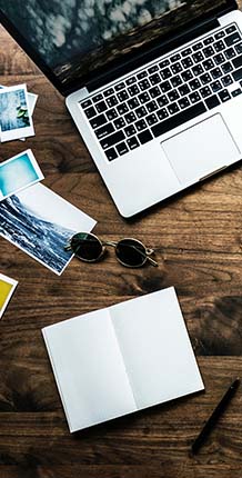 Laptop, photos, and sunglasses on table