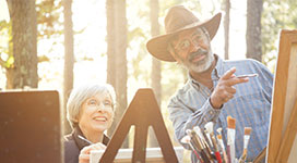 Older couple with painting supplies out in the woods.